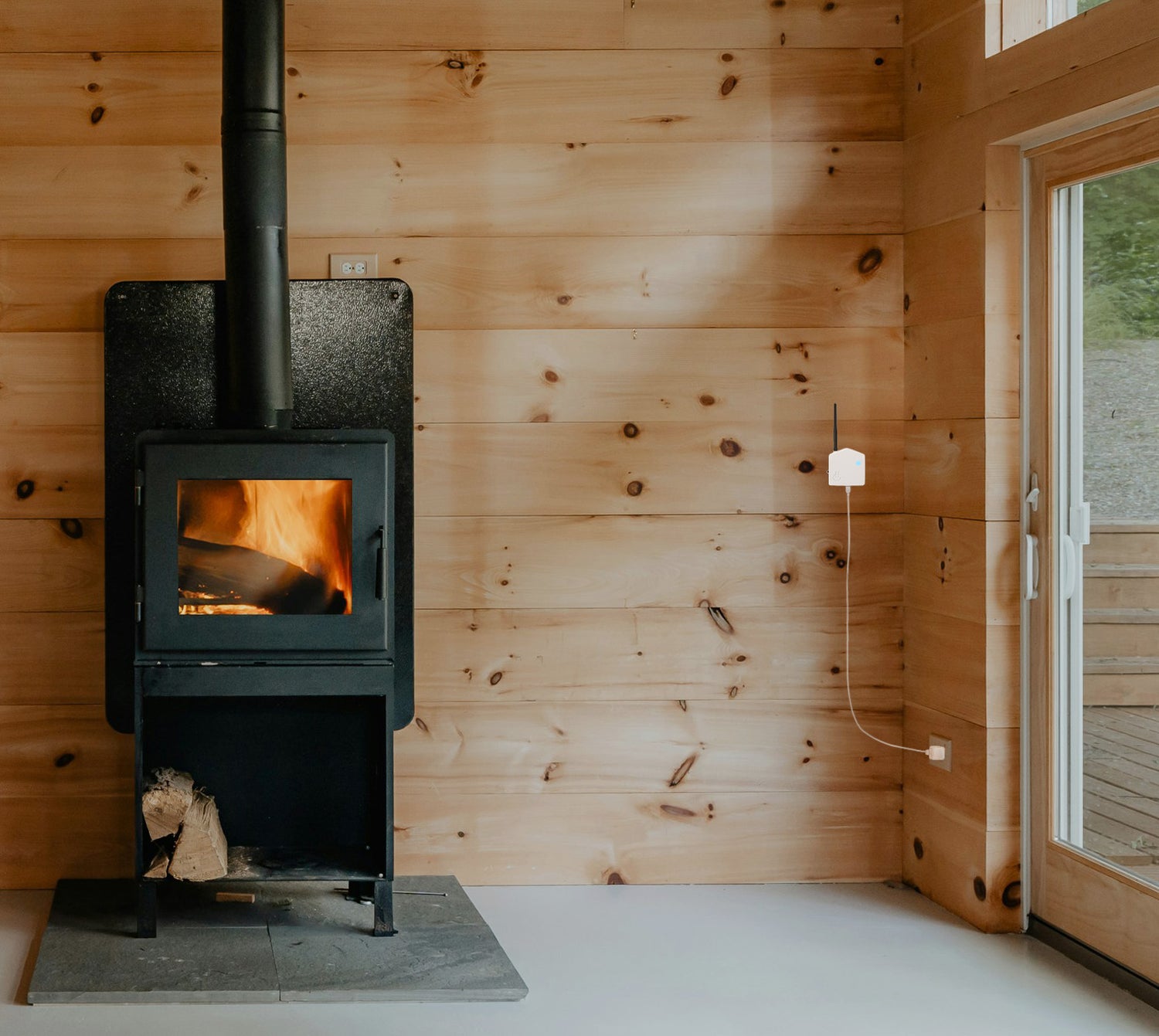 Wood-burning stove in a room with wooden walls and a door with Hygge Monitor watching temperature and Humidity